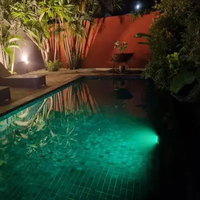 a swimming pool at night with lights in the water at Villa Casa Jamika in Seminyak