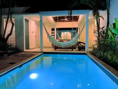 a hammock in front of a house with a pool at Rove Pool Villa Seminyak in Seminyak