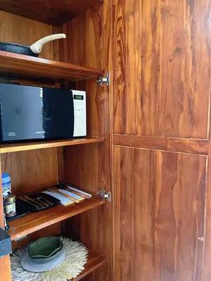 a kitchen with wooden cabinets with a microwave at Rove Pool Villa Seminyak in Seminyak