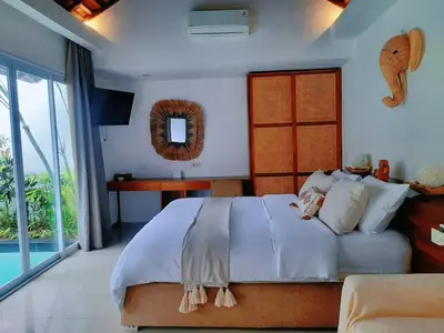 a bedroom with a large white bed and a television at Rove Pool Villa Seminyak in Seminyak