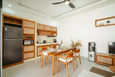 a kitchen with a table and chairs and a refrigerator at Villa Tirtha at Nara Villa in Seminyak