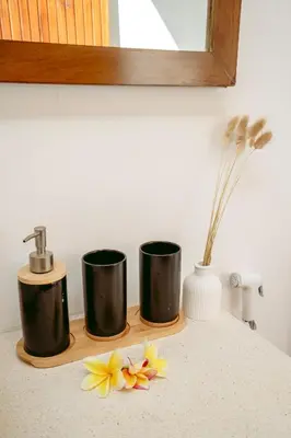 a bathroom counter with three cups and flowers on it at Villa Tirtha at Nara Villa in Seminyak