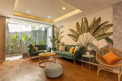 a living room with green couches and a large plant at Cove Renata in Seminyak