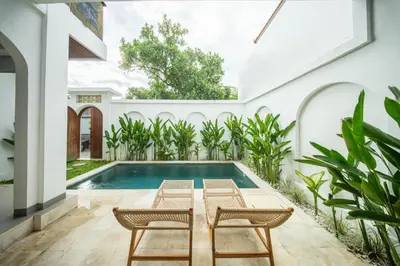 an indoor pool in a house with two chairs and a table at Modern and Quiet 2BR Villa in Seminyak Central with Private Pool in Denpasar