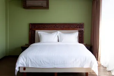 a bed with white sheets and pillows in a green bedroom at Ducat Living in Canggu