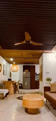a living room with a ceiling fan and a table at Villa Wild in Seminyak