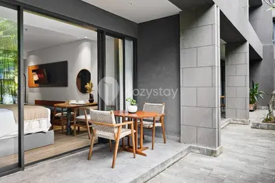 a room with a bed and a table and chairs at Aranya by Kozystay - Nusa Dua in Nusa Dua