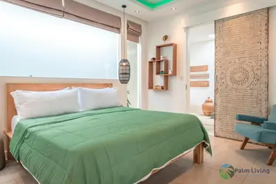 a bedroom with a green bed and a blue chair at Villa Babar in Canggu