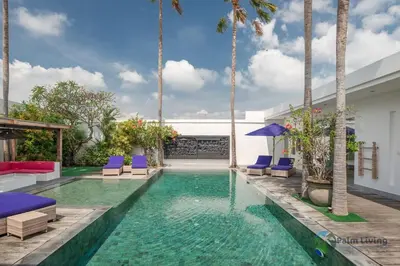 a swimming pool with blue chairs and palm trees at Villa Babar in Canggu