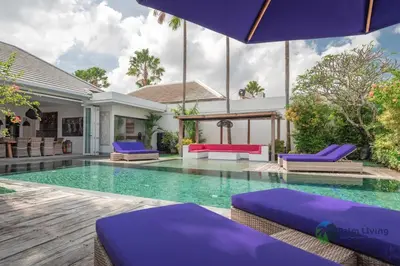 a villa with a swimming pool and purple lounge chairs at Villa Babar in Canggu