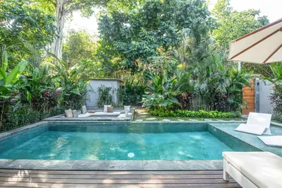 a swimming pool in a garden with a table and chairs at Stylish 5BR Designer Villa, 400m to the Ocean in Canggu