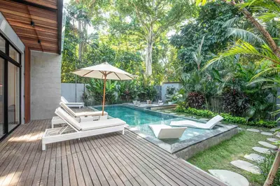a pool with two lounge chairs and an umbrella at Stylish 5BR Designer Villa, 400m to the Ocean in Canggu