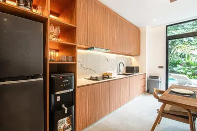 a kitchen with wooden cabinets and a dining room at Stylish 5BR Designer Villa, 400m to the Ocean in Canggu