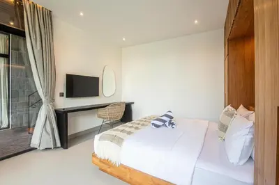 a bedroom with a bed and a desk and a television at Elegant 5BR Tropical Escape Just 400m to Beach in Canggu