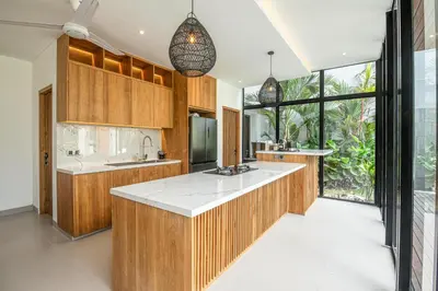 a kitchen with wooden cabinets and a large window at Elegant 5BR Tropical Escape Just 400m to Beach in Canggu