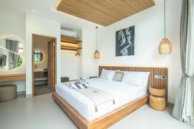 a bedroom with a large white bed with a wooden headboard at Elegant 5BR Modern Villa Steps from Café Del Mar in Canggu