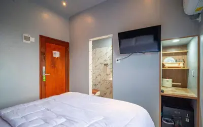 a bedroom with a bed and a flat screen tv at Hotel Dakozi Living in Kuta