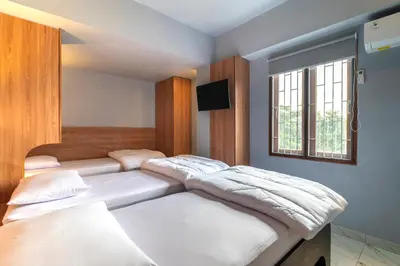 two beds in a room with a window at Hotel Dakozi Living in Kuta