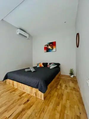 a bed in a room with a wooden floor at Persada Loft Bali in Seminyak