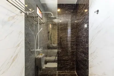 a bathroom with a shower with black tiles at Villa Balidamai in Kerobokan
