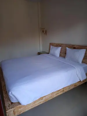 a large wooden bed with white sheets and pillows at Erick house in Seminyak