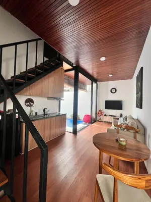 a living room with a spiral staircase and a table at Oemah Ozzy Villa 2 Bedroom With Privat Pool in Seminyak
