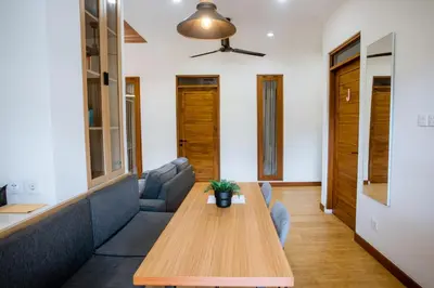 a living room with a wooden table and a couch at Jemma Home Warm & Simple 3BR Stay in Denpasar near Sanur in Pesanggaran