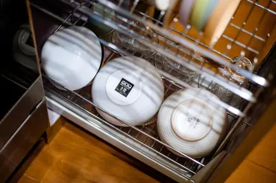 a pile of plates in a dishwasher at Jemma Home Warm & Simple 3BR Stay in Denpasar near Sanur in Pesanggaran