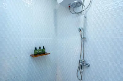 two bottles of wine sitting on a shelf in a shower at Nirvana Villa by Betterplace in Seminyak