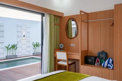 a bedroom with a bed and a balcony with a pool at Nirvana Villa by Betterplace in Seminyak