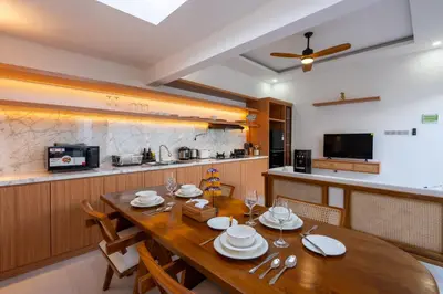 a dining room with a wooden table and a kitchen at Nirvana Villa by Betterplace in Seminyak