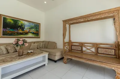 a living room with a couch and a painting on the wall at Soma Villa by Betterplace in Jimbaran