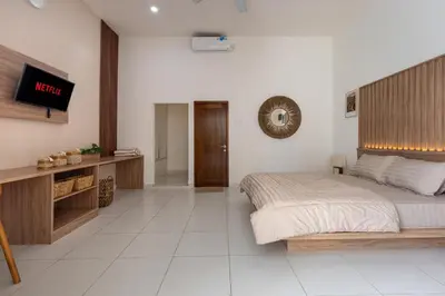 a bedroom with a bed and a tv on a wall at Soma Villa by Betterplace in Jimbaran