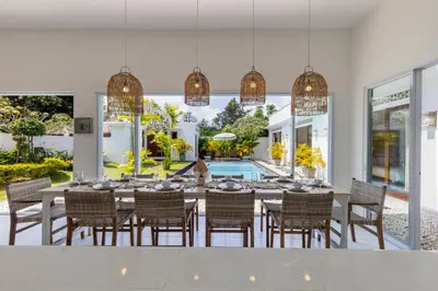 a dining room with a table and chairs and a pool at Soma Villa by Betterplace in Jimbaran