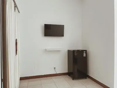 a black refrigerator in a room with a tv on the wall at Kubu Van Helen in Legian