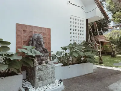 a statue in front of a building with plants at Kubu Van Helen in Legian