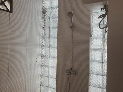 a shower in a bathroom with a glass wall at Kubu Van Helen in Legian