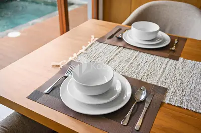 a table with two cups and plates and silverware at deTasia Villa by Kozystay - Jimbaran in Jimbaran
