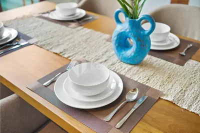 a table with white plates and a blue vase on it at Gracia Villa by Kozystay - Jimbaran in Jimbaran