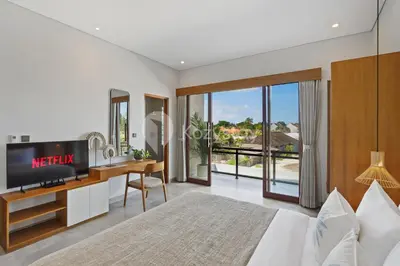 a bedroom with a bed and a desk with a tv at Gracia Villa by Kozystay - Jimbaran in Jimbaran