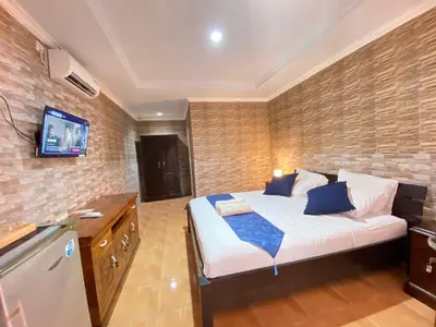 a bedroom with a bed and a tv on a brick wall at ABI Hotel2 - 1 minute to the Beach and 1 second to the Mall in Ngurah Rai International Airport
