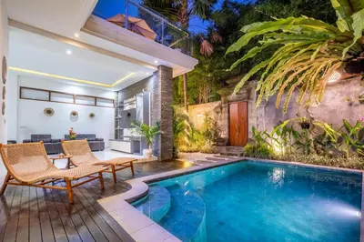 an outdoor living room with a swimming pool and a house at Villa Naga by JB Villas in Seminyak