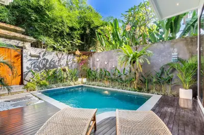 a swimming pool in a backyard with two chairs at Villa Naga by JB Villas in Seminyak