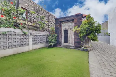 a backyard with a green lawn in front of a building at Collection O Bali Sanur near Bali Mandara Hospital in Sanur
