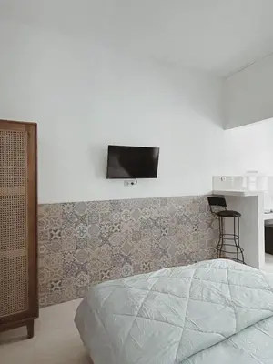 a bedroom with a bed and a tv on the wall at Sukanadi's Homestay in Legian