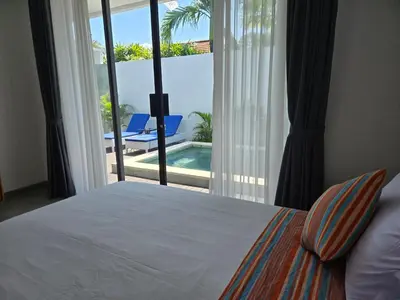 a bedroom with a bed and a view of a pool at Sunflower Bali Villa 3BR Legian Double Six Beach in Seminyak