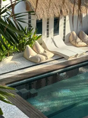 a swimming pool with chaise lounges next to a resort at Villa Vela in the heart of Seminyak in Seminyak