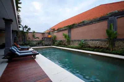 a swimming pool with a chaise lounge next to a building at The Visala Boutique Suites Seminyak in Seminyak