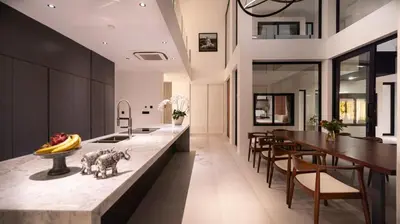 a kitchen with a long counter with chairs and a table at House of Light 5bed villa in Canggu