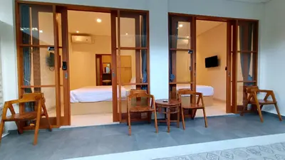 a room with chairs and a table and a bed at AA Inn Kuta Beach in Ngurah Rai International Airport